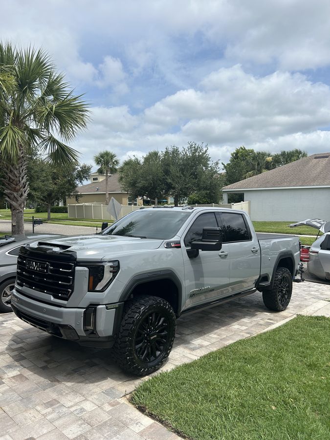 White GMC Sierra 2500HD AT4, lifted on black wheels, freshly finished