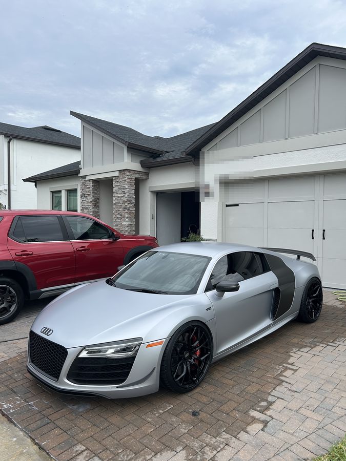 Silver Audi R8 V10 with a carbon side blade, finished and parked on block paving