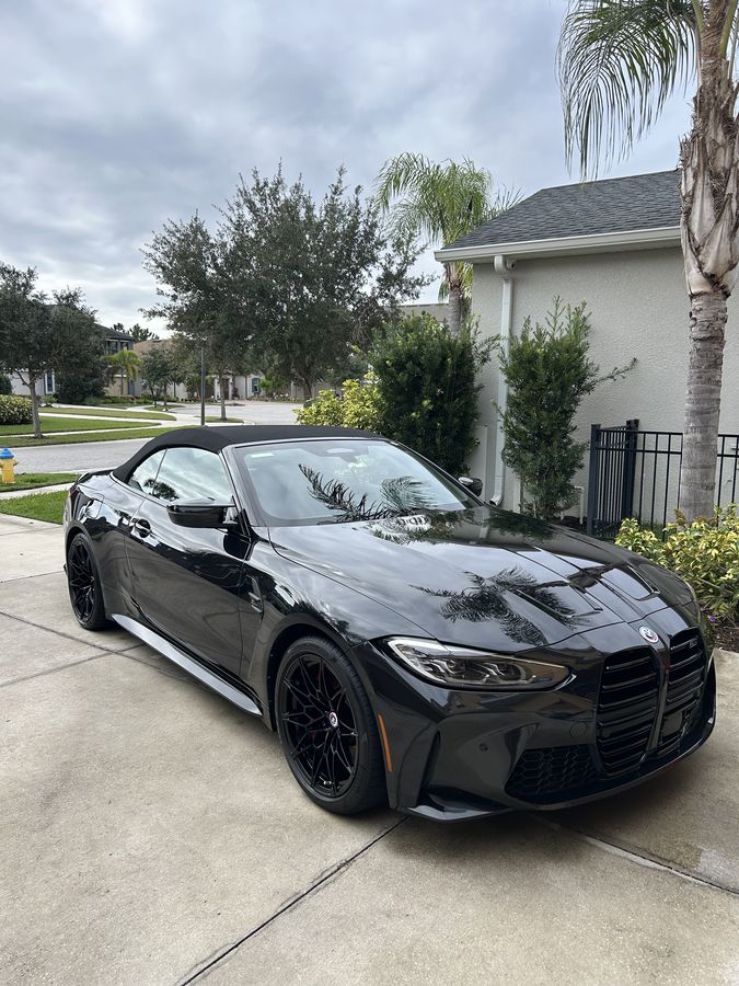 Black BMW M4 Competition convertible, roof up, deep gloss across the bonnet