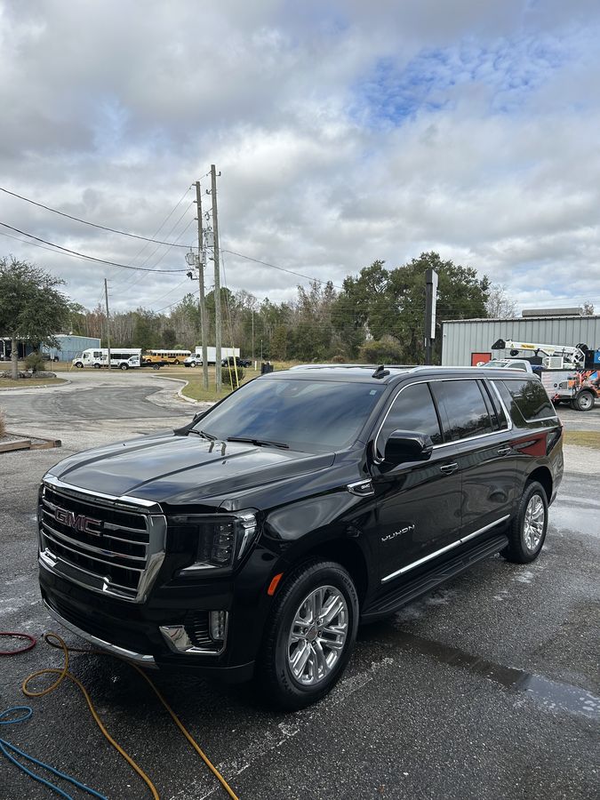 Black GMC Yukon XL, still wet, on a commercial lot