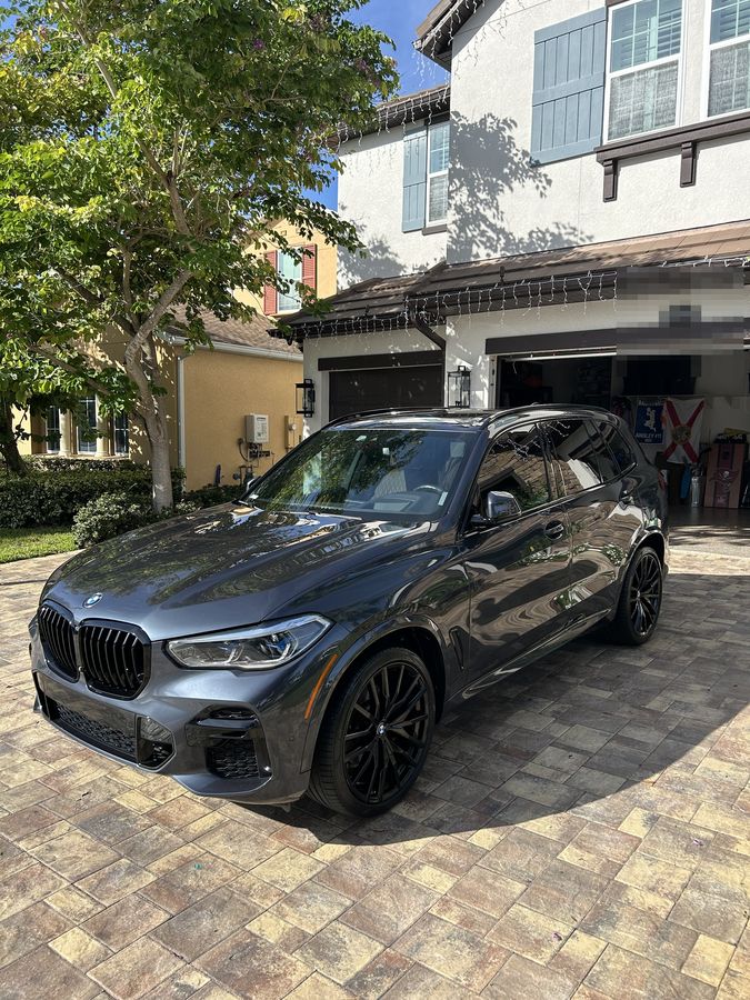 Grey BMW X5 M Sport on block paving, the garage reflected in its flank