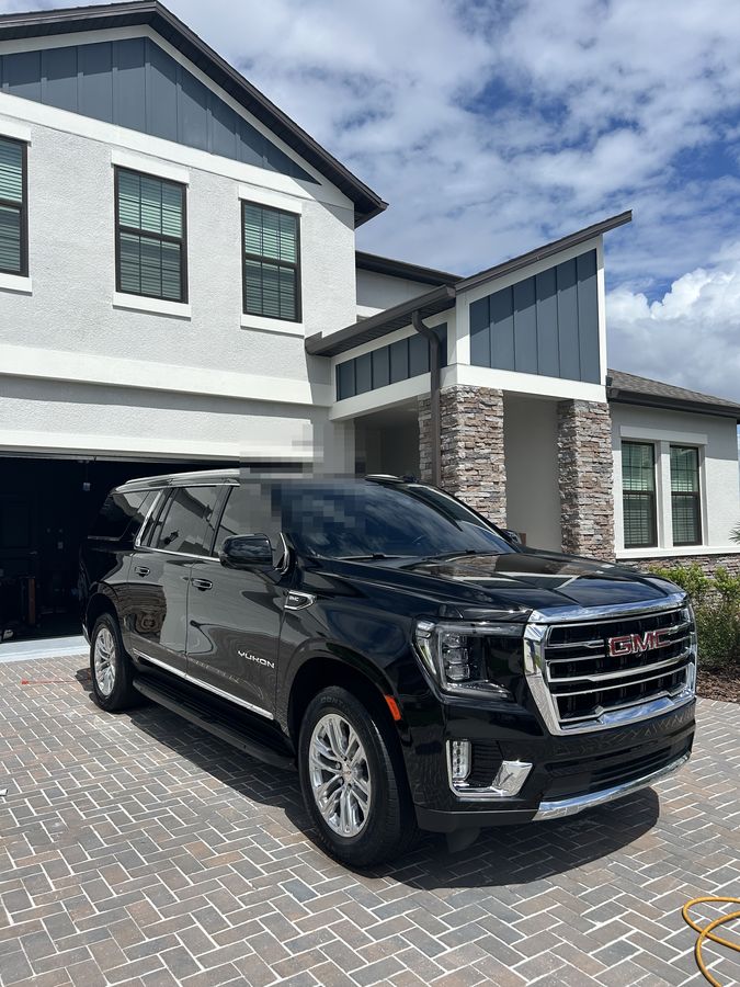 Black GMC Yukon on block paving outside a house
