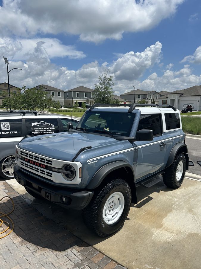 Two-door Ford Bronco in blue-grey, washed down on a driveway