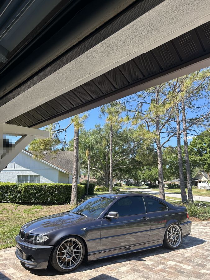 Grey BMW M3 coupe on polished wheels, detailed under a carport